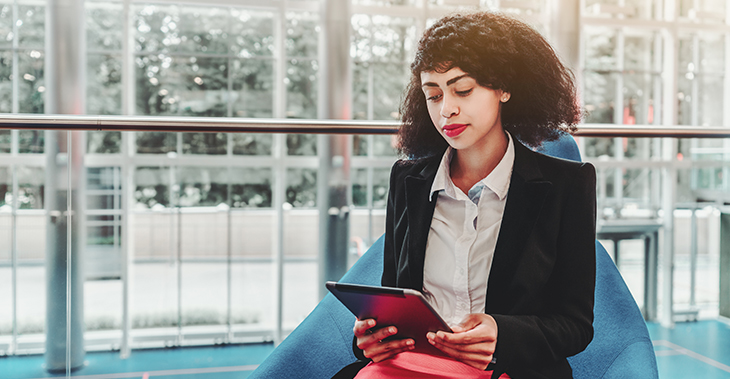 Everlytic | Blog | Launch Your Next Product or Service with the Sideways Sales Letter | Blog Image | Professional Lady Sitting on Blue Chair Looking at Tablet in an Open Office Space