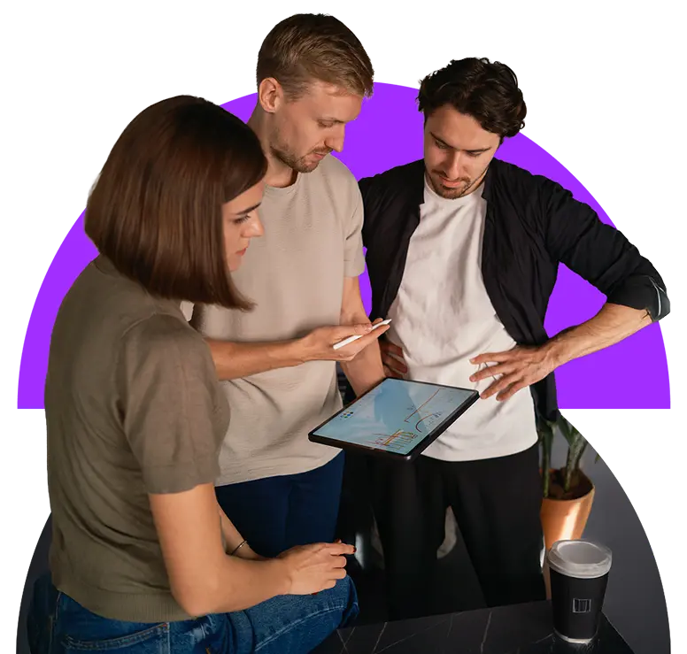 A team standing around each other looking at something on a tablet.